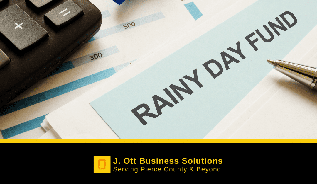 A stack of paperwork with a pen and calculator. Text on a paper reads: Rainy Day Fund