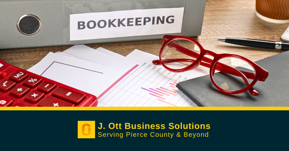 A desktop with red glasses and calculator with a binder that reads Bookkeeping.