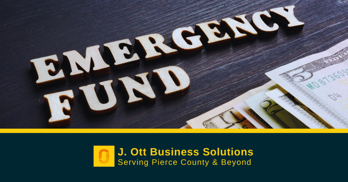 Wooden letters spell out: Emergency Fund on a dark desktop with cash nearby.
