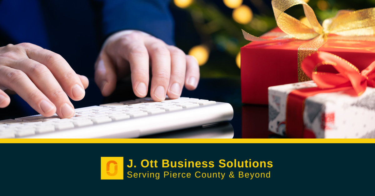 A person sits at a desk with wrapped holiday gifts and a laptop.